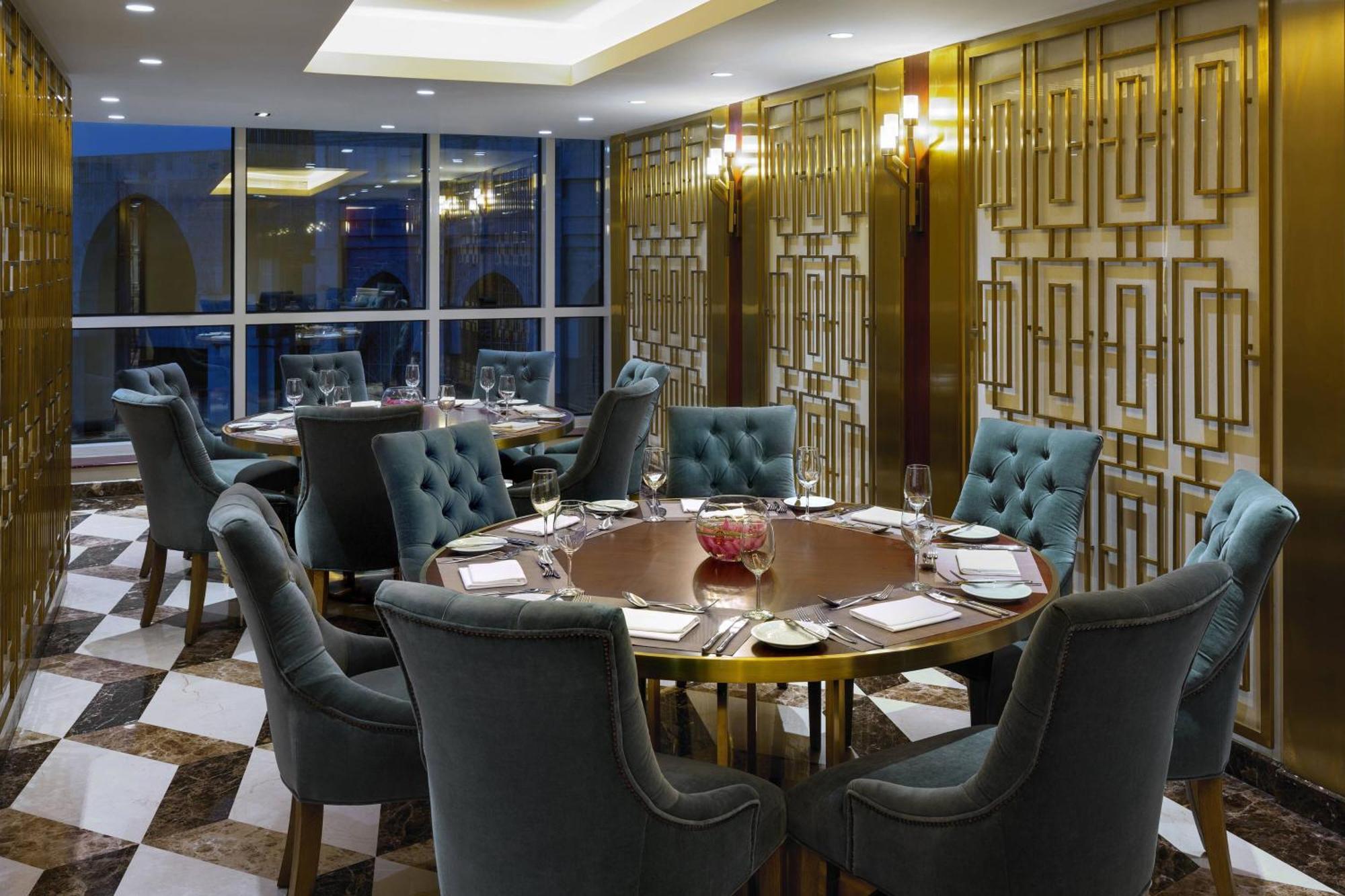 Sheraton Makkah Jabal Al Kaaba Hotel Mekka Exterior foto The photo shows an elegant dining room with a sophisticated ambiance. It features a round wooden table at the center, surrounded by plush chairs upholstered in a soft, teal fabric. The room has a stylish décor, highlighted by a geometrically patterne